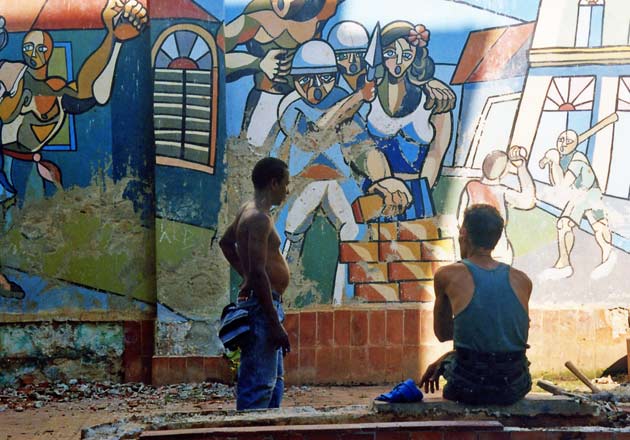 Havana, Cuba. Two bricklayers resting in front of a mural honouring bricklaying