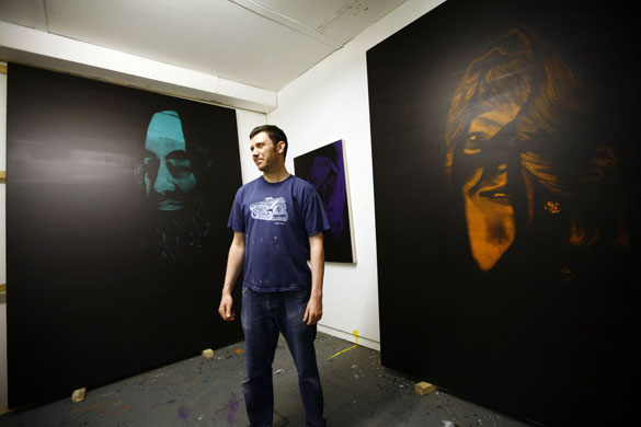 Artist Leigh Clarke stands in front of his painting at his studio in Hackney