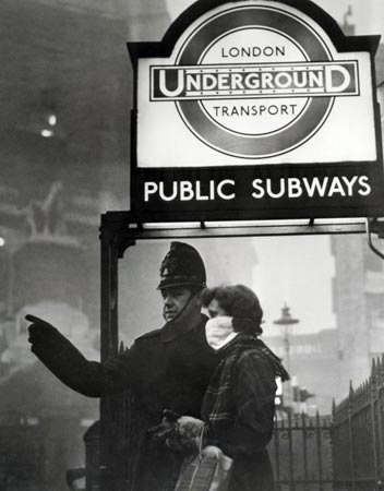 A policeman gives directions to a woman wearing a facemask against the smog in 1957