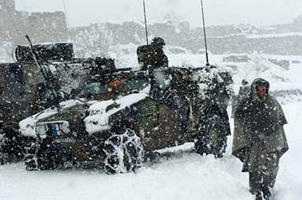 An Afghan villager passes French soldiers