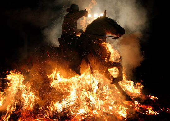 A man rides a horse through a bonfire in the Spanish village of San Bartolomé de Pinares to honour St Anthony the Abbot