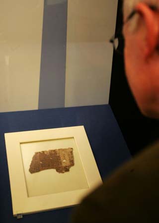 A visitor looks at the 'Book of Psalms' fragment from The Dead Sea Scrolls at the 'Sacred : Discover what we share' exhibition in the British Library, London,