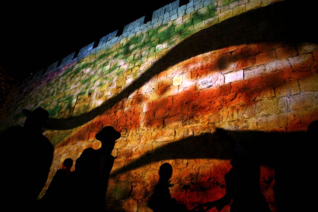 People walk past an image projected on Jerusalem's old city walls on April 21, 2008 during an audio-visual light show for the Jewish holiday Passover