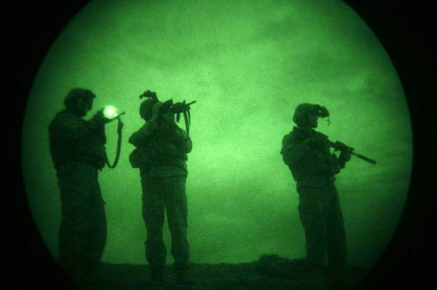 In an image made through light enhancing equipment, a  U.S soldier of the 101st Airborne Division stands with others as he looks through his gun during a night patrol in Mandozai, in Khost province, Afghanistan