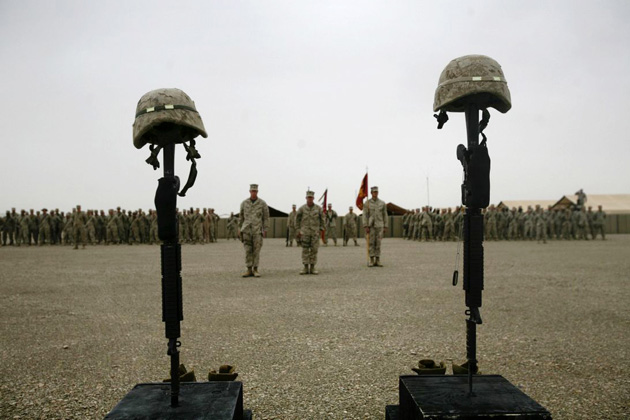 U.S. Marines stand before the helmets, weapons, dogtags and boots of two fallen marines during a ceremony in their honor at Camp Bastion
