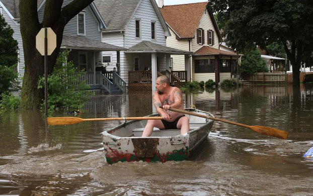 Charles Wittke rows down a flooded street in front of his home in Cedar Rapids