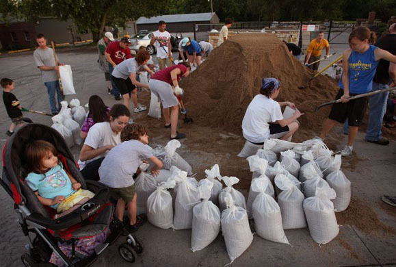 Employees and Volunteers fill sandbags at Kings Material in Coralville
