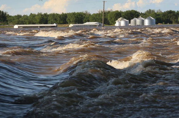 Flood water from the Iowa River rages through farmland near Oakville