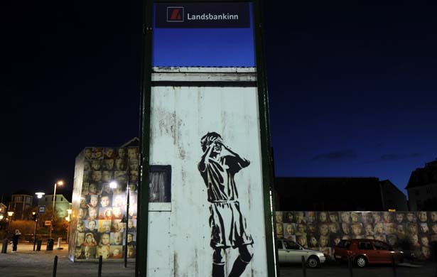 A drawing shows a man holidng his head under an advertisement of Icelandic bank Landsbanki in Reykjavik