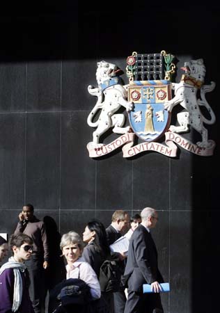 Members of the public walk beneath the coat of arms outside Westminster City Hall