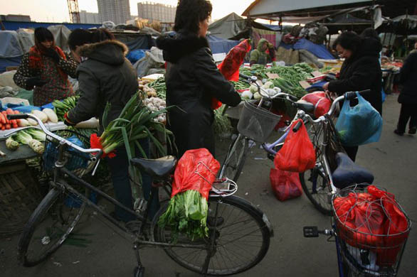 Chinese women buy vegetables with plastic bags at a food market. The Chinese Government has announced a nationwide ban on stores distributing free plastic bags from June 1