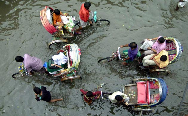 Cycle rickshaws wade through ankle-deep water after a heavy rain in Dhaka, Bangladesh