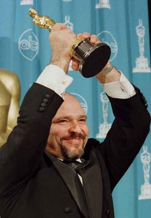 Anthony Minghella holds up his best director Oscar for The English Patient at the Academy Awards in March 1997 