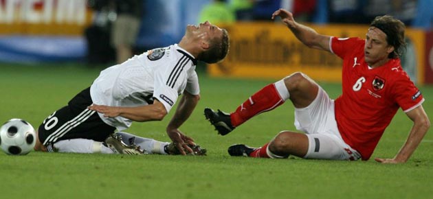The German forward Lukas Podolski scraps with Austrian midfielder Rene Aufhauser during a goalless first half. Photograph: Yuri Kadobnov/AFP