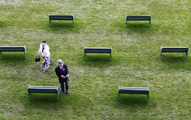 Racegoers walk past seats in the Royal enclosure
