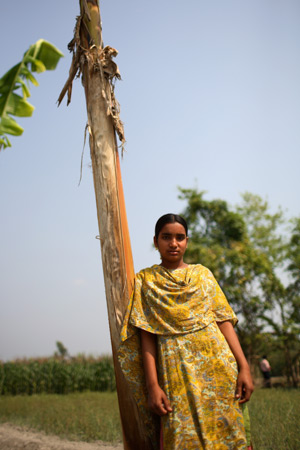 A girl leans against a tree