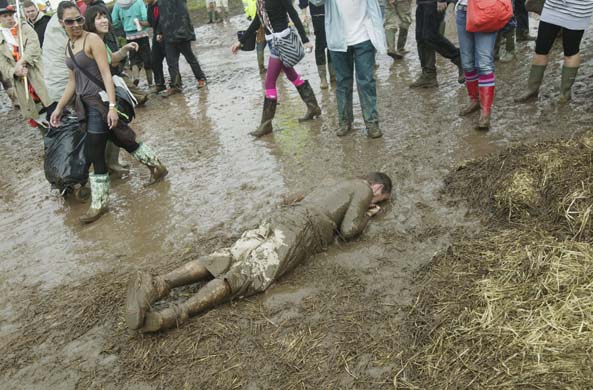 A festival goer lies in the mud at Bestival