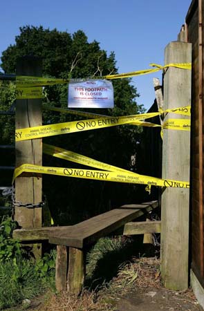 A sign hangs on the gate of a public footpath