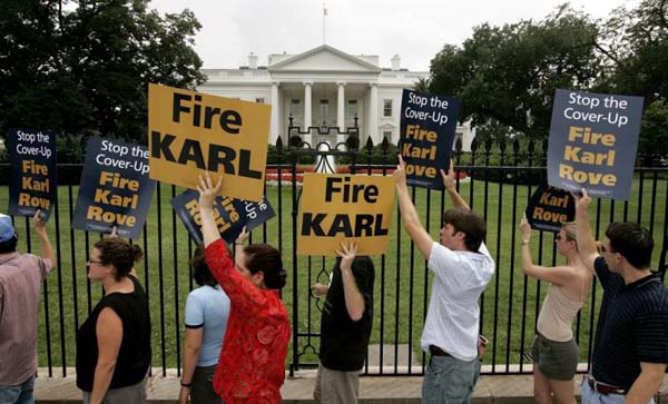 Protesters hold signs during a march calling for the firing of Karl Rove