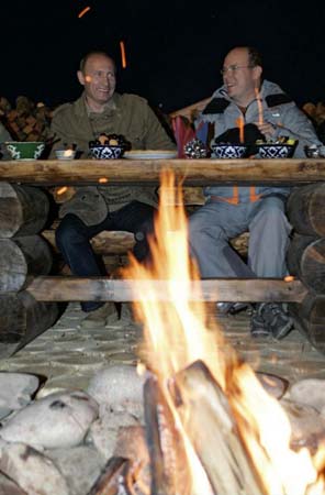 Putin and Prince Albert II sit by a campfire