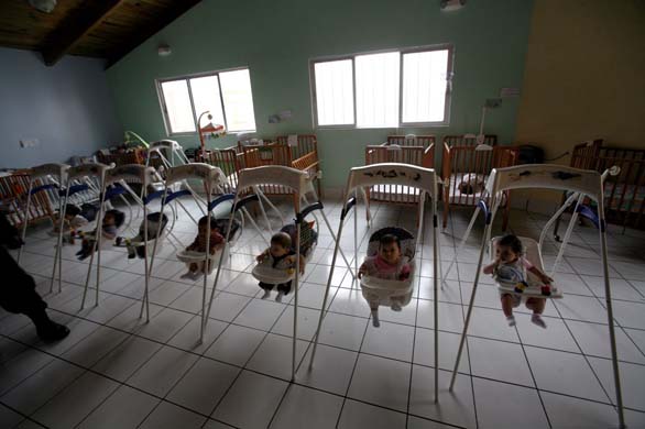 Children sit in bouncing chairs at the Casa Quivira children's home