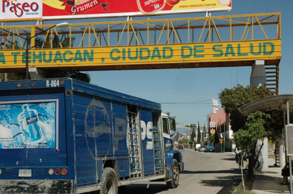 A bottled water truck passed under a bridge bearing the slogan - Tehuacan, City of Health