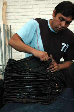 A worker sorts through a pile of newly sewn Guess jeans