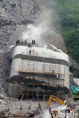Rescue workers prepare to drill holes for explosives in order to break a collapsed bridge to search for bodies
