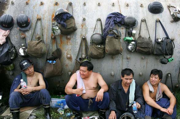 Rescue workers rest after plugging a breach in a dike