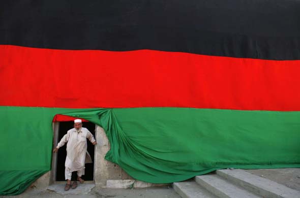 A man poses beside a large flag as the country celebrates Independence day