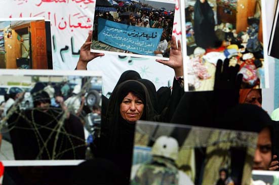 Women carry pictures showing raids by US soldiers and mourning Iraqis during protests against military operations
