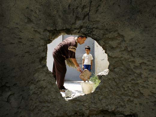 A man cleans up after four mortar shells landed in the Abu Dashir neighbourhood