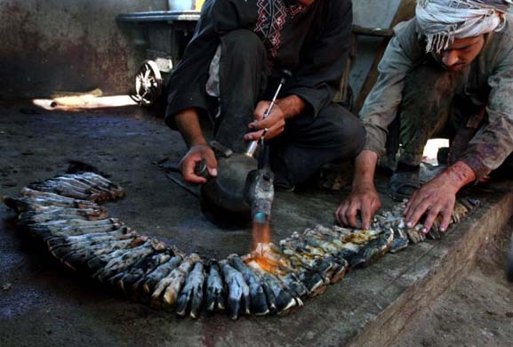 A butcher and his colleague burn sheep legs before selling