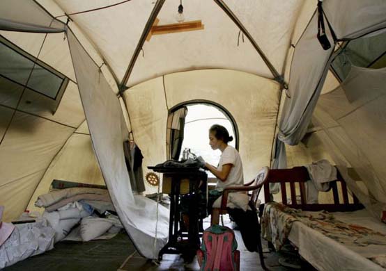 A woman sews clothing in her tent to earn money for her family