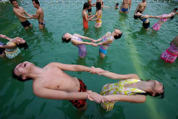 Instructors demonstrate positions during a water yoga class at a fitness centre