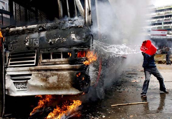 A man throws water at a burning bus
