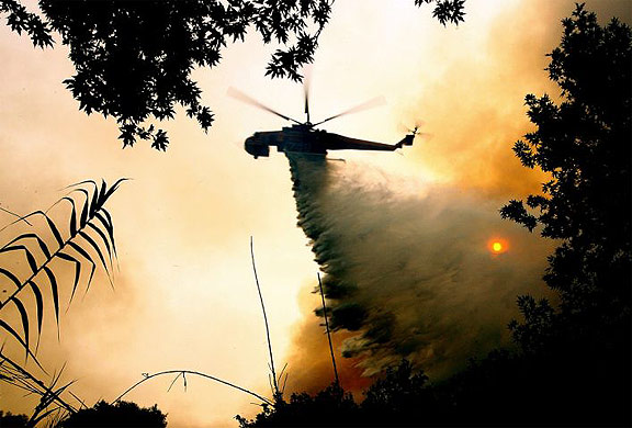 A helicopter drops water in the forest over the Pelopio village near ancient Olympia