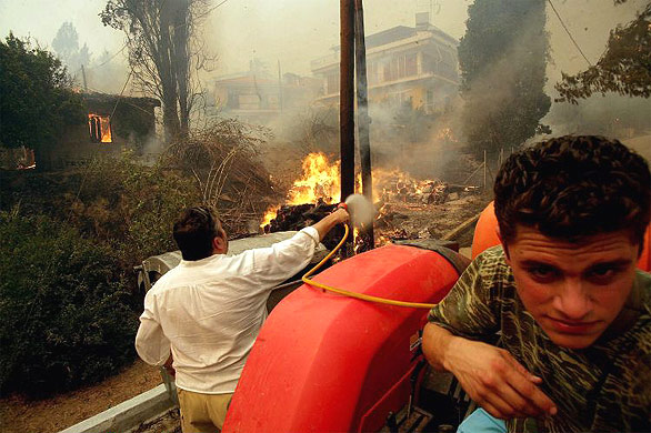 Men using a tractor try to extinguish a fire near ancient Olympia
