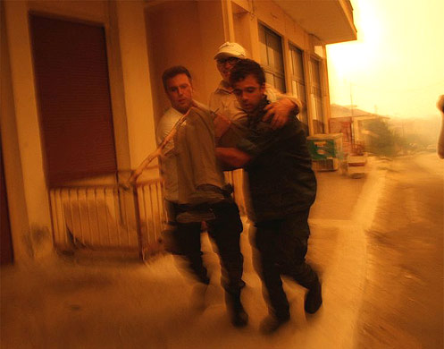 Greek soldiers evacuate an old man from a village near ancient Olympia