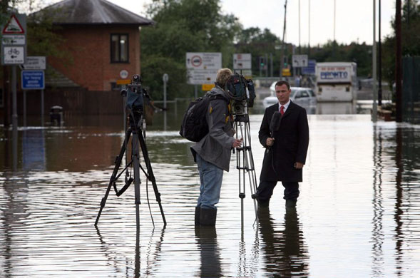 :  A TV camera crew report in a flooded street in Tewkesbury