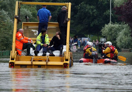 A boat passes a lorry struggling through floodwater in Tewkesbury