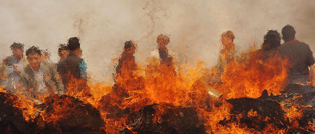 Officials watch as opium products go up in flames during an official ceremony