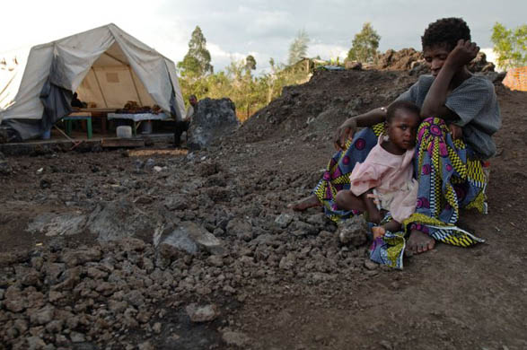 A mother and a child sit outside a cholera centre run by Medecins Sans Frontieres