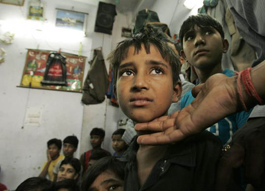 A child rights activist touches a child worker rescued during raids at a place that employs children to do embroidery work