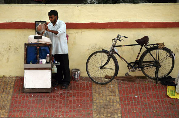 An Indian man is shaved by a street barber ahead of the Hindu festival of Diwali