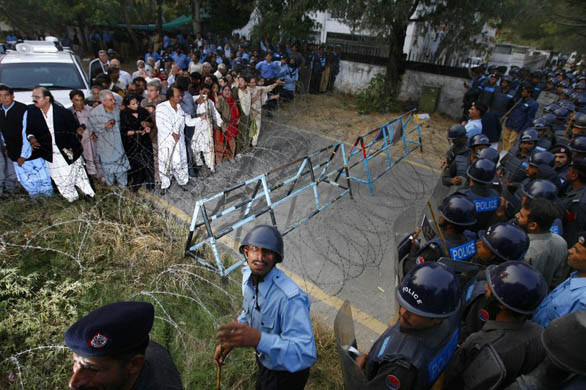 The vehicle carrying opposition leader Benazir Bhutto, and her supporters, is blocked by police and a barbed wire blockade outside her home