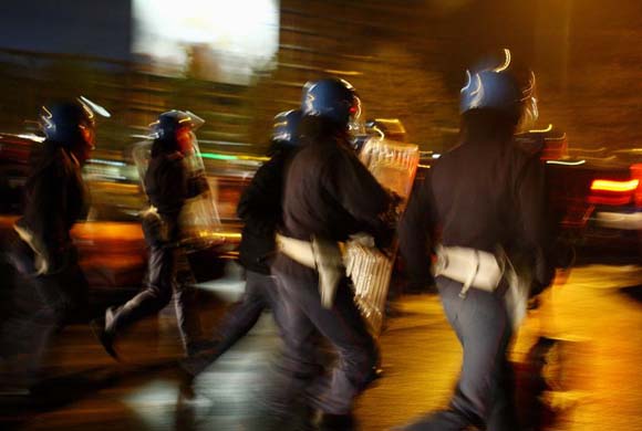 Riot police run along the street