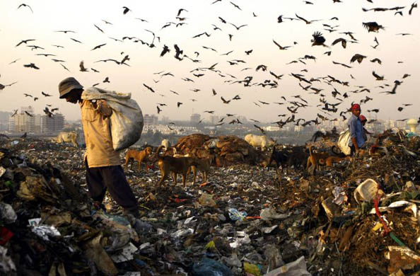 A man searches through rubbish for scrap at a landfill site