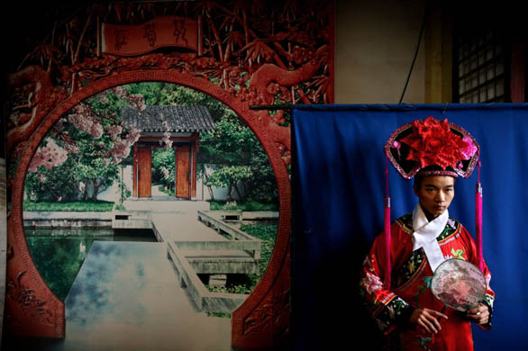 A man has his picture taken wearing traditional clothing in the Forbidden City