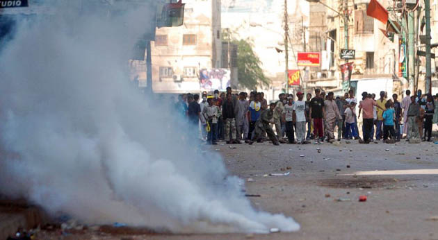 Smoke rises up from teargas shells fired by police at supporters of Benazir Bhutto
